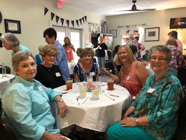 A group of women are sitting at tables in a room.