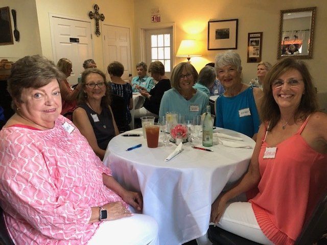 A group of women are sitting around a table with drinks