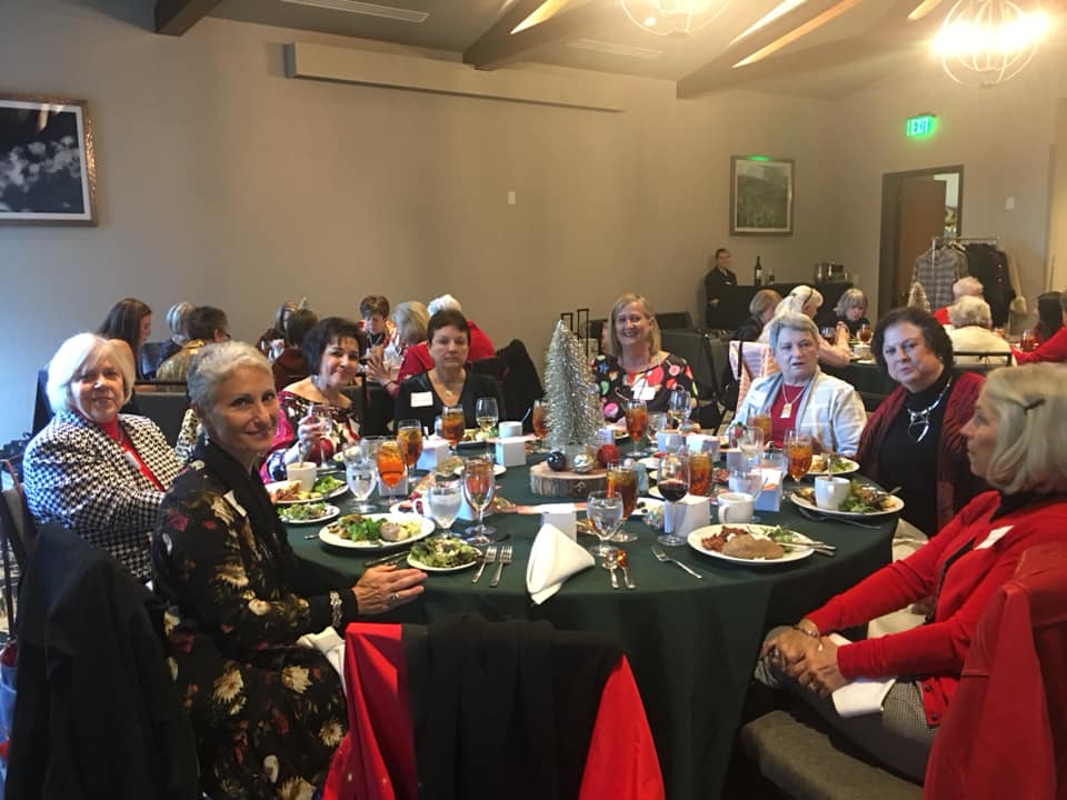 A group of women are sitting at a table with plates of food.