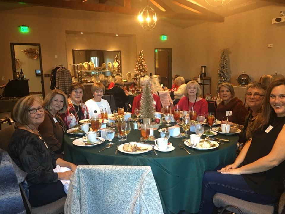 A group of women are sitting around a table with plates of food.