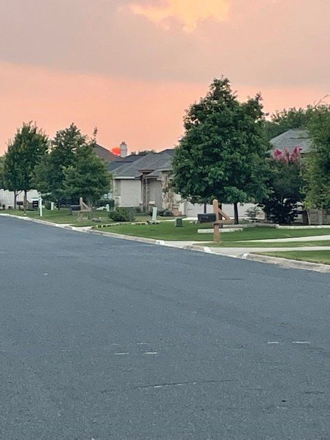 A row of houses on a residential street with a sunset in the background.