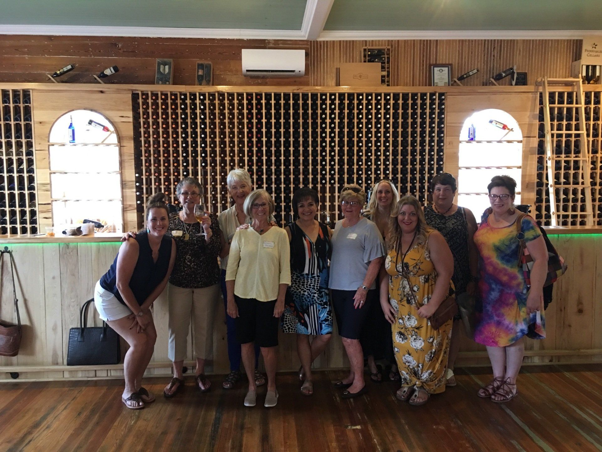 A group of women are posing for a picture in a wine cellar.