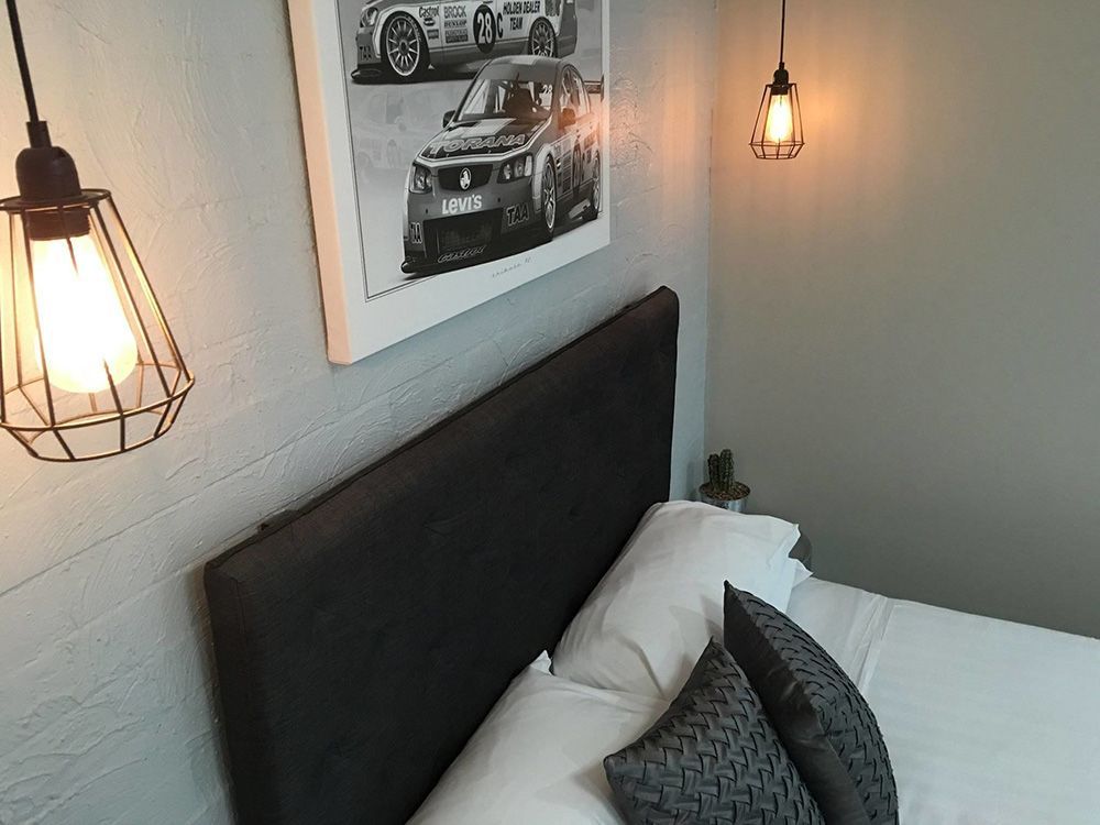 There Is A Picture Of A Race Car On The Wall Above The Bed — Country Leisure Dubbo in Dubbo, NSW