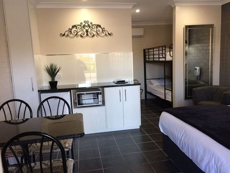 A Hotel Room With A Bunk Bed, Table And Chairs — Country Leisure Dubbo in Dubbo, NSW