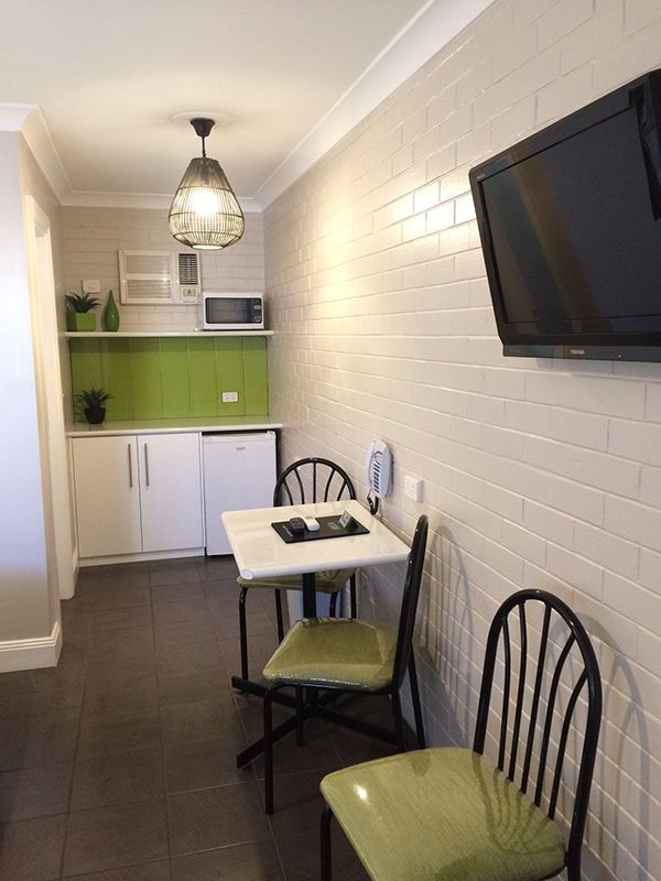 A Small Kitchen With A Table And Chairs And A Flat Screen Tv — Country Leisure Dubbo in Dubbo, NSW
