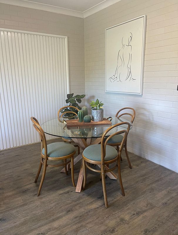 A Dining Room With A Glass Table And Chairs And A Painting On The Wall — Country Leisure Dubbo in Dubbo, NSW