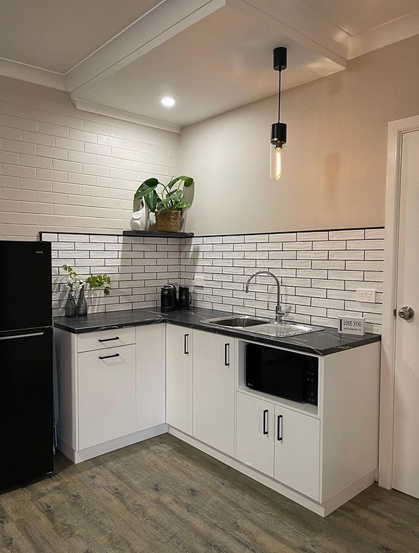 A Kitchen With White Cabinets, A Black Refrigerator, A Sink, And A Microwave — Country Leisure Dubbo in Dubbo, NSW