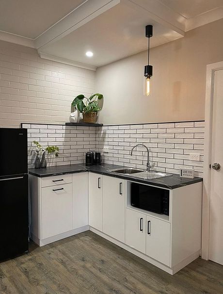 A Kitchen With White Cabinets, A Black Refrigerator, A Sink, And A Microwave — Country Leisure Dubbo in Dubbo, NSW