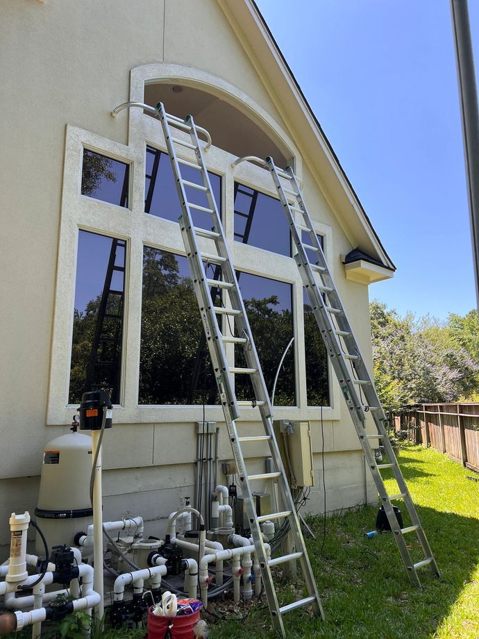 Two ladders are sitting on the side of a house.