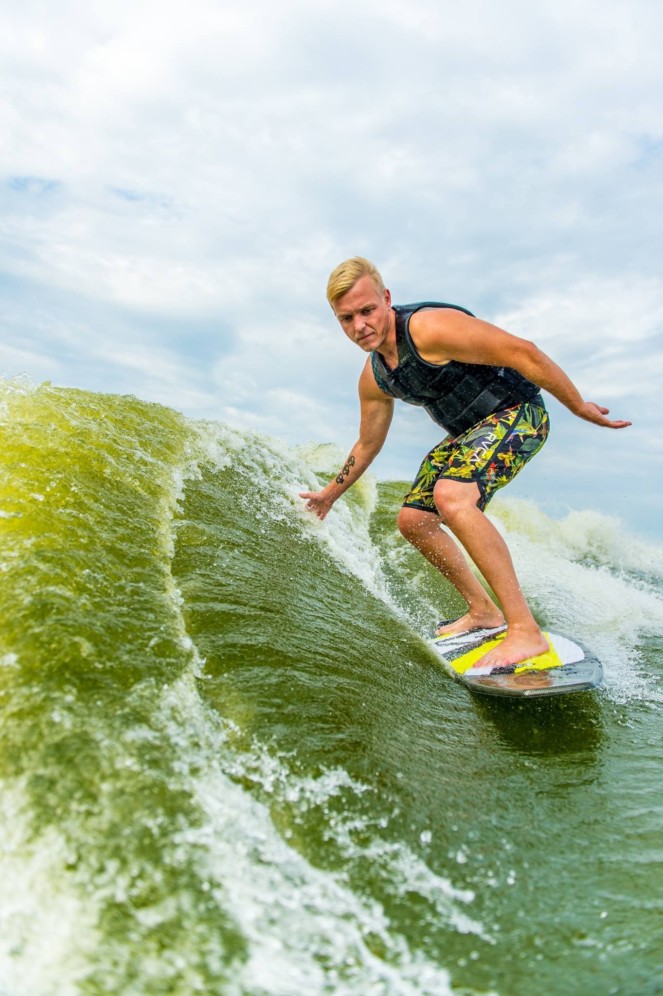 A man is riding a wave on a wakeboard in the water.