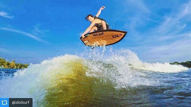 A man is riding a wave on a wakeboard in the air.