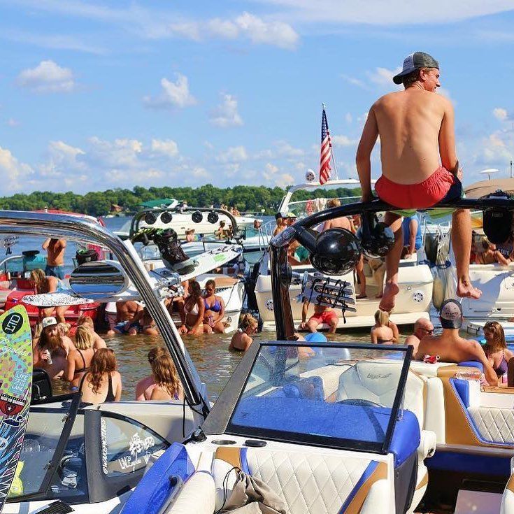 A man is sitting on the back of a boat in the water