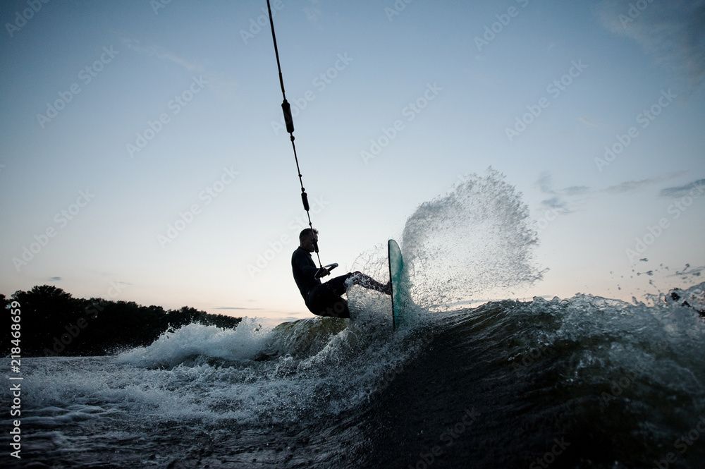 A man is riding a wave on a wakeboard in the water.