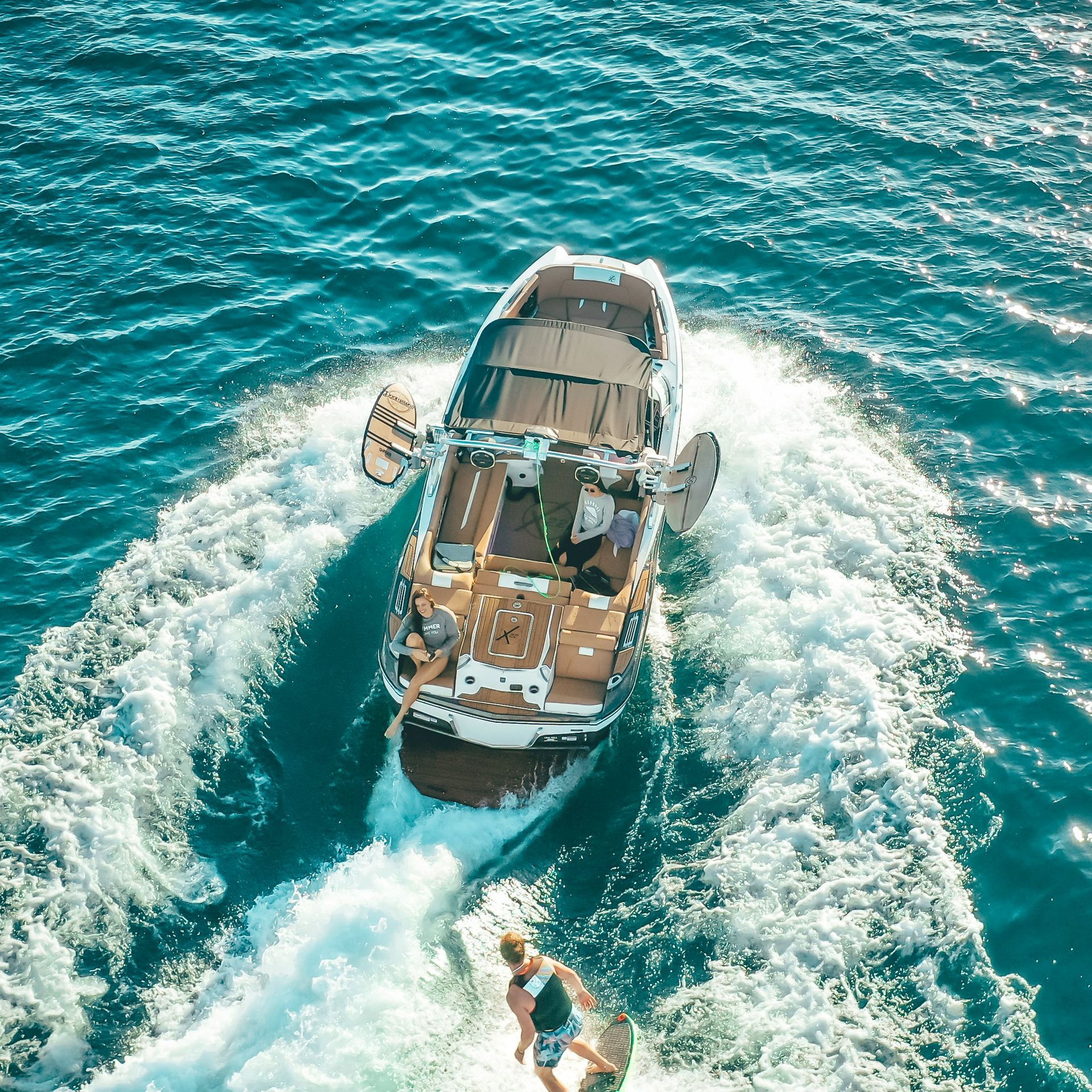 An aerial view of a boat and a person wakesurfing in the ocean.