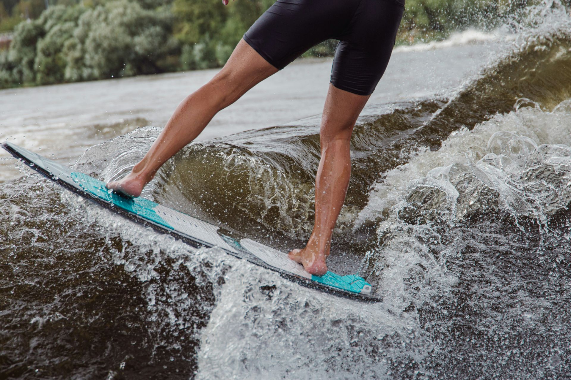 A person is riding a wave on a wakeboard in the water.