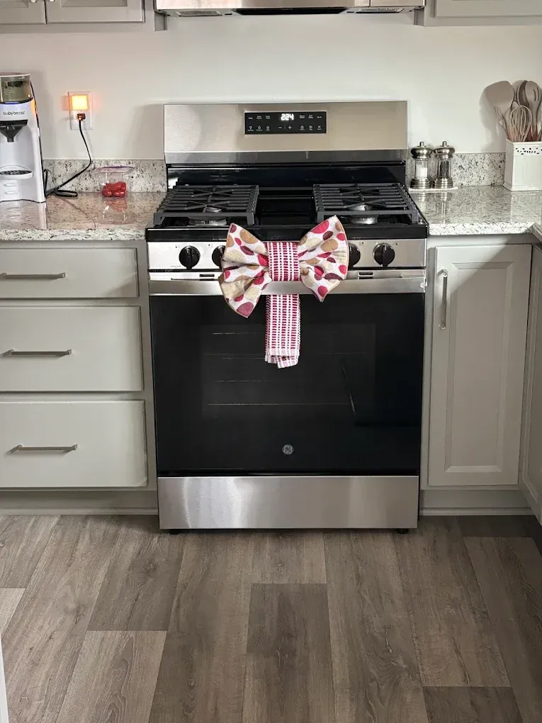 A kitchen with a stainless steel stove; a bow and towel hang on the oven.