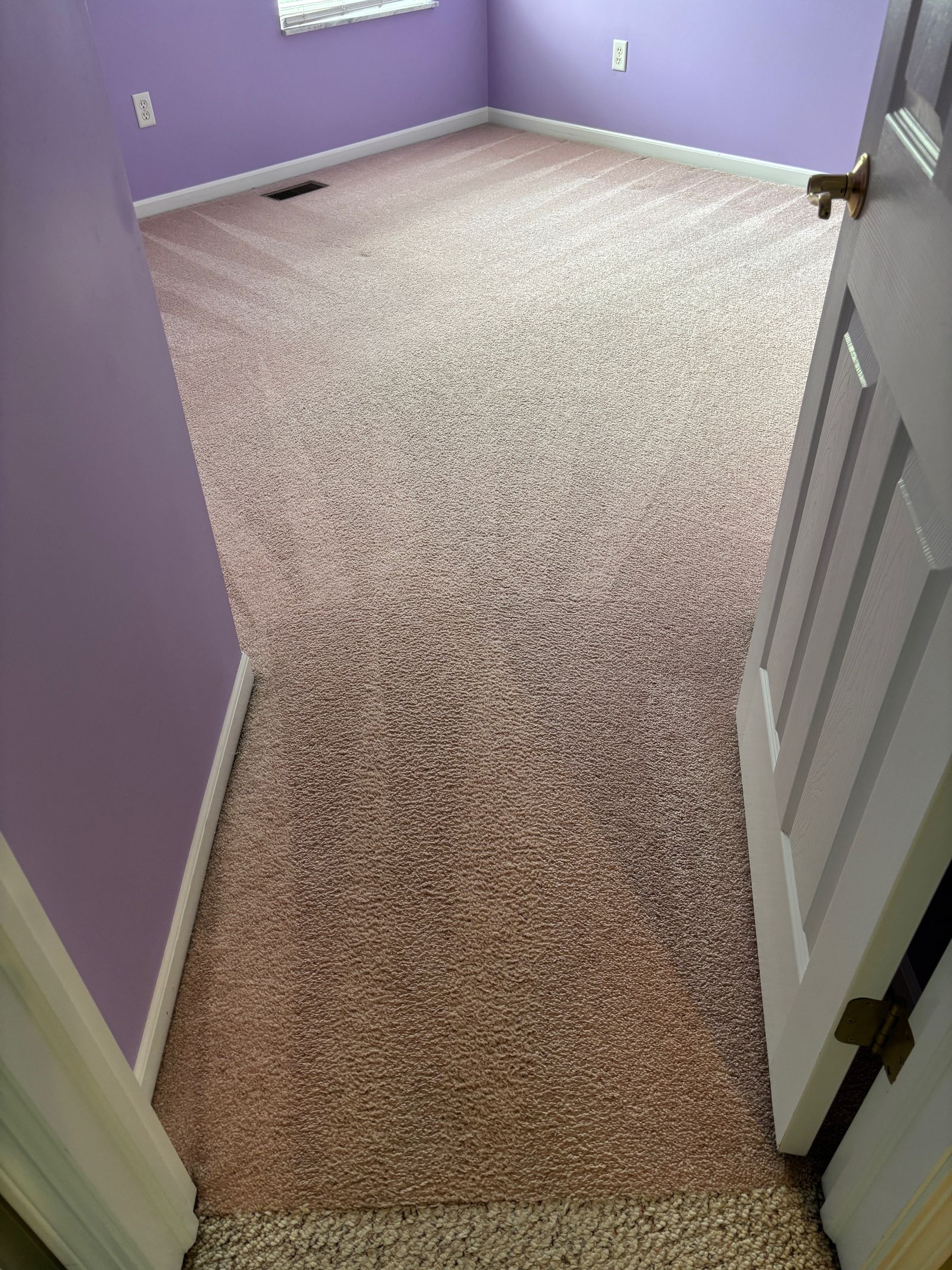 Room with purple walls and patterned brown carpet, seen from doorway.