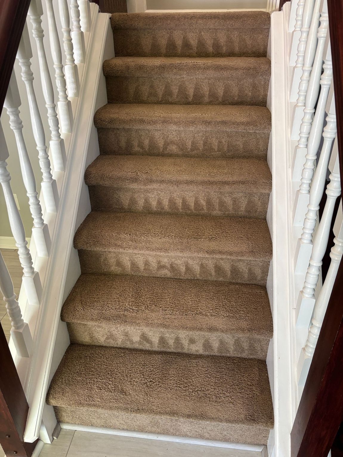 Carpeted staircase with white railing and brown steps.