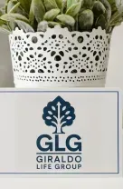 A desk features a white pot with a green plant next to a card with the blue