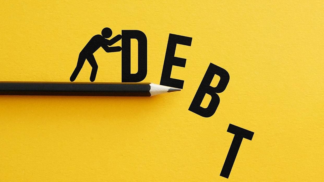 A black pencil rests on a yellow background, propping up the letters of the word 