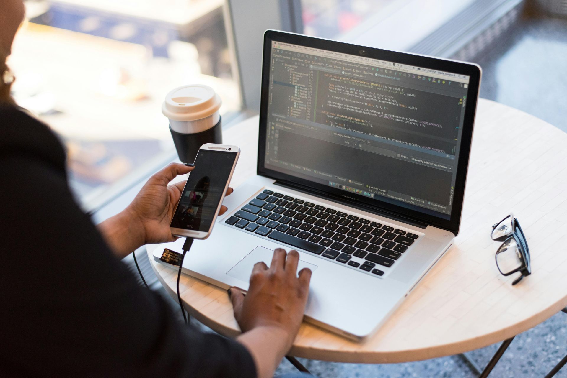 A person is sitting at a table with a laptop and a cell phone.