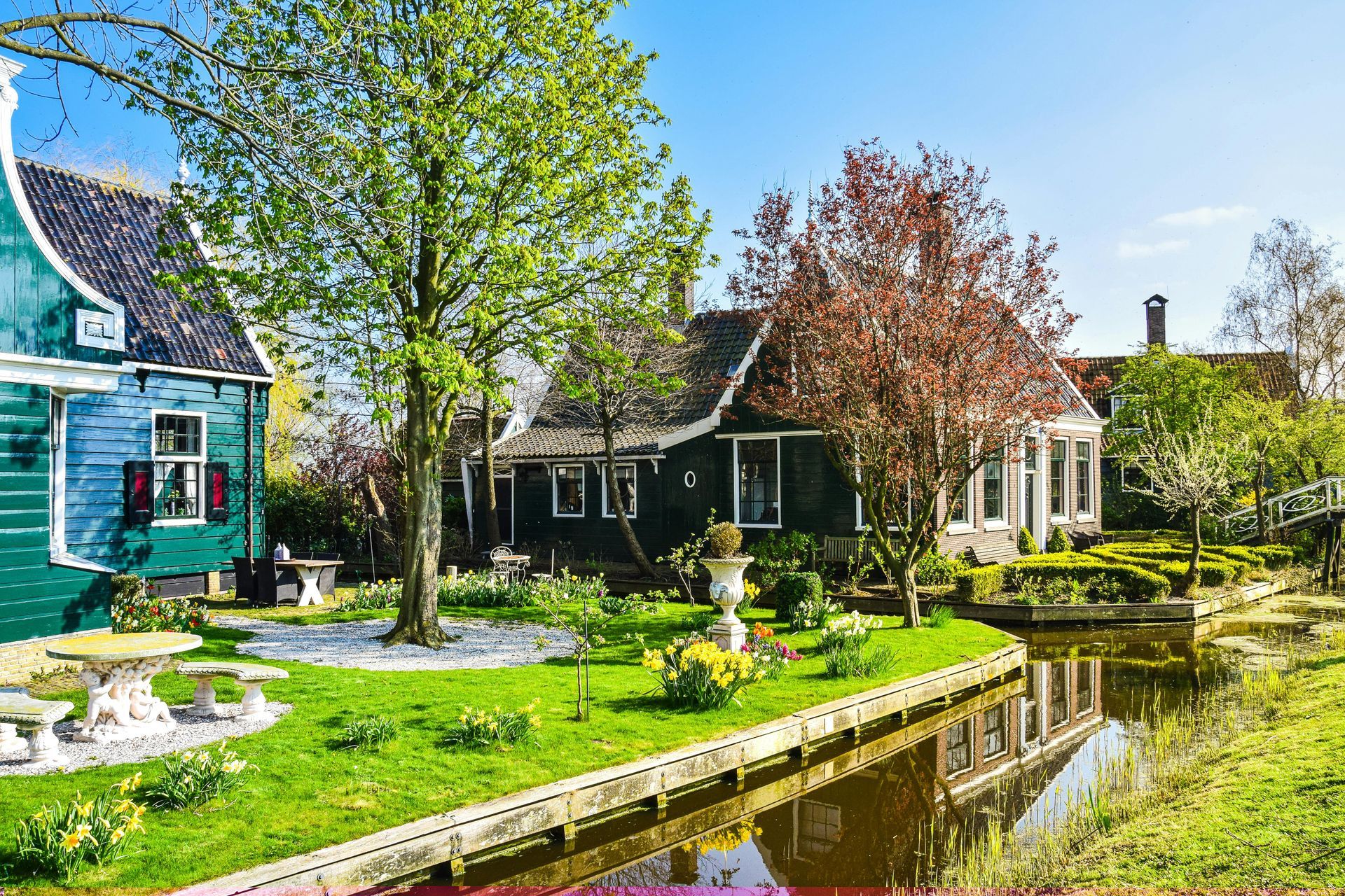 Canal-side cottages with gardens and trees on a sunny day