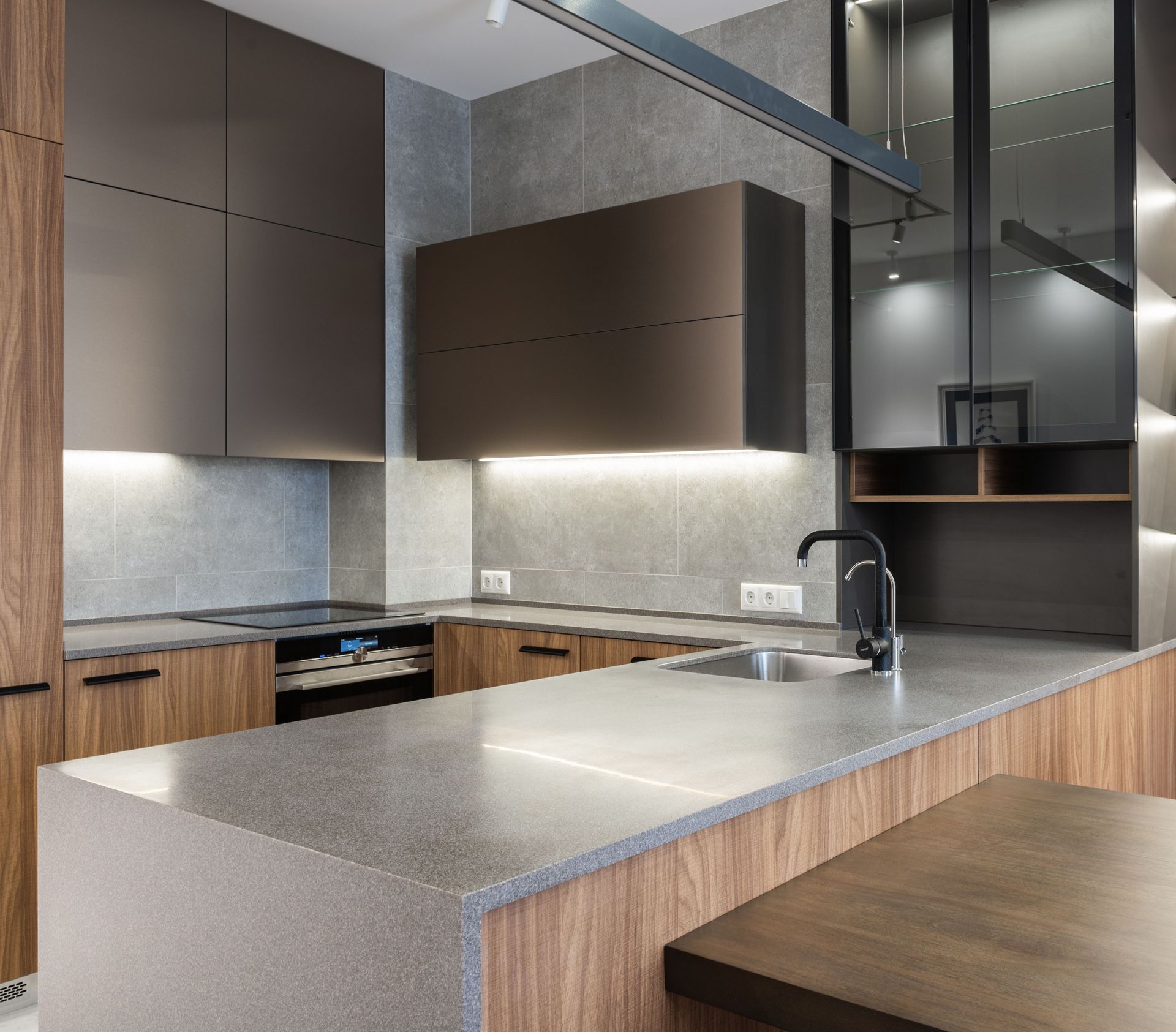 Modern kitchen with wood and gray cabinets, large island, stainless sink, and stone countertops.