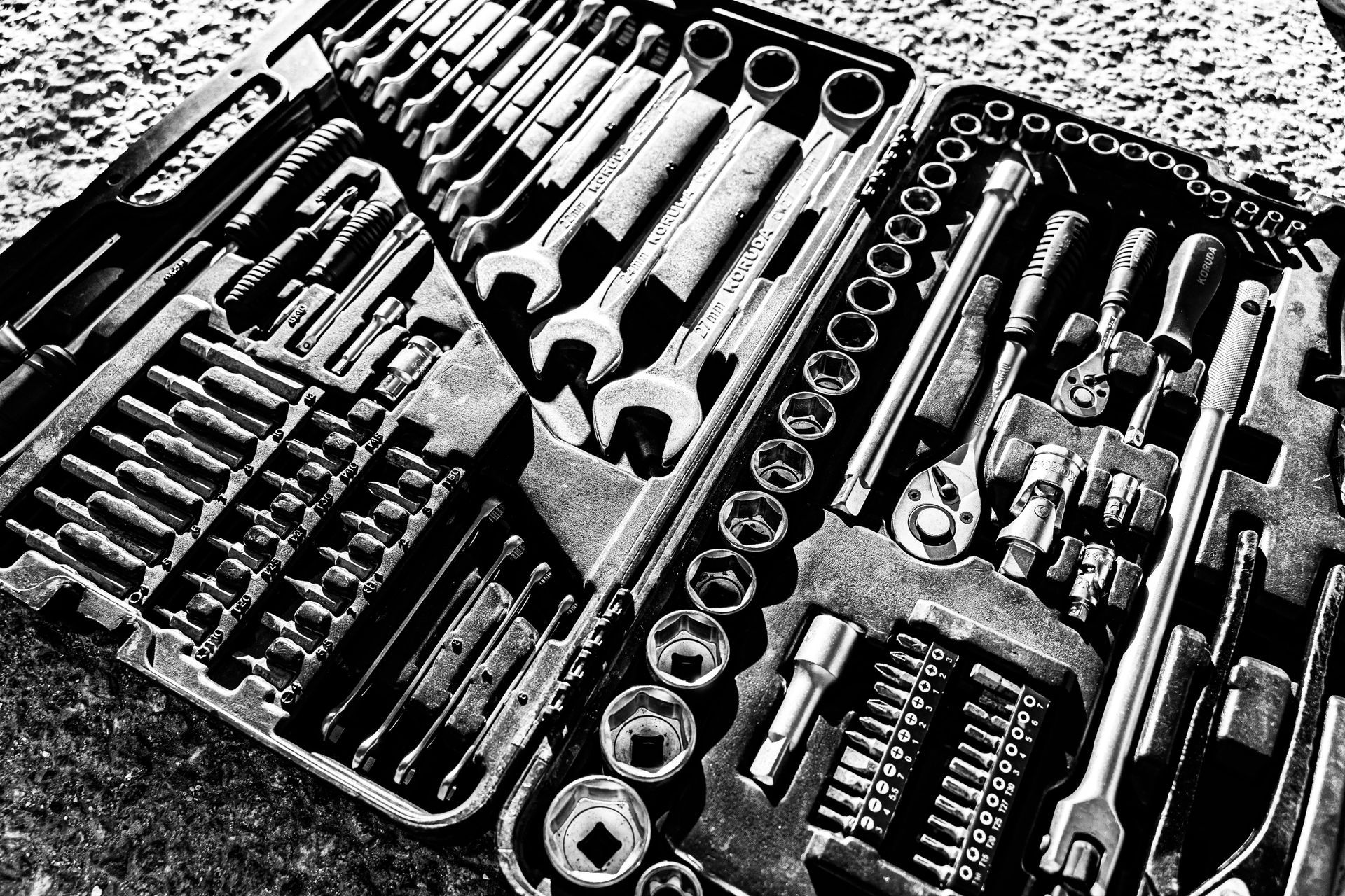 An open plastic tool kit containing a variety of organized metal wrenches, sockets, and ratchets.