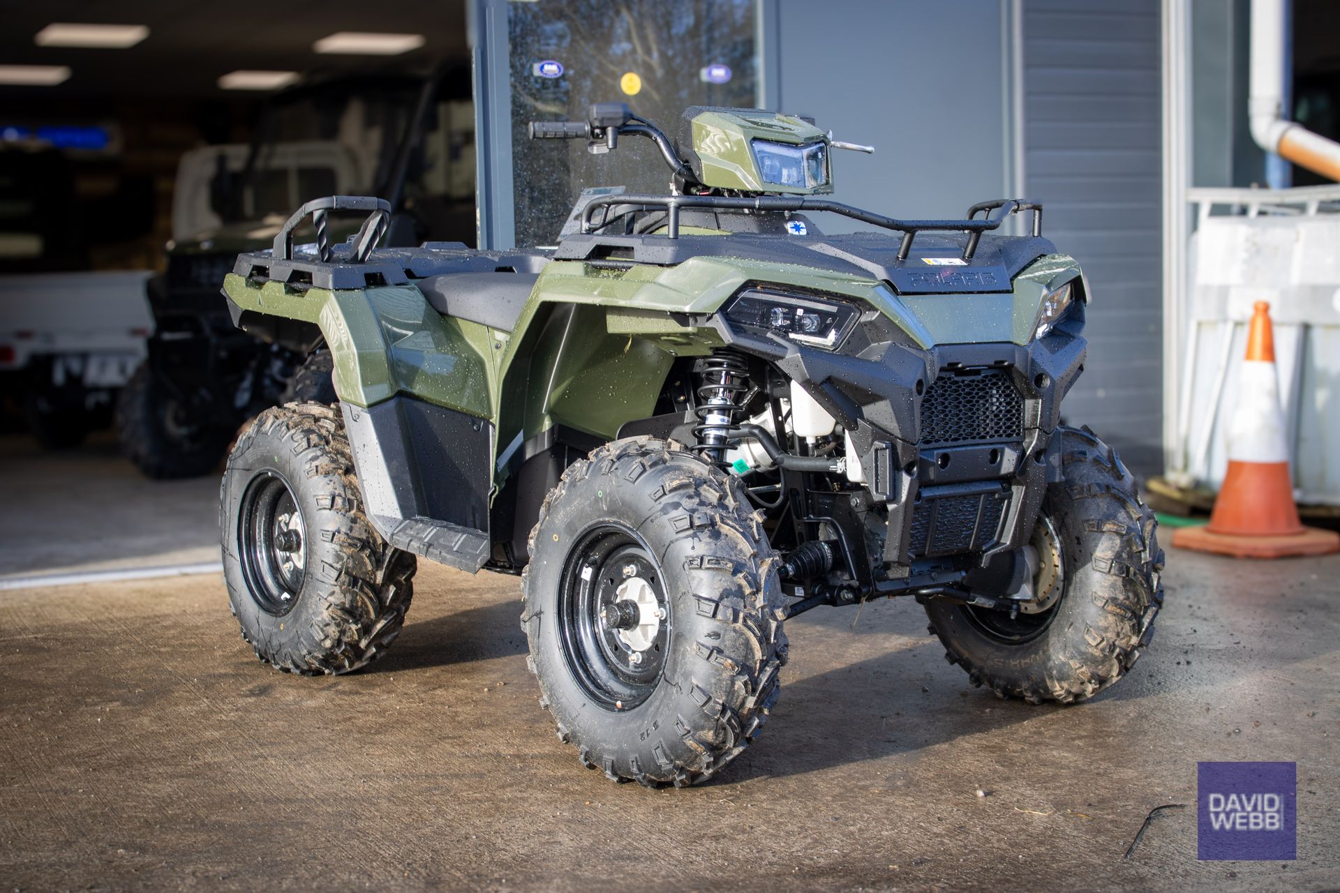 A green atv is parked in front of a building.