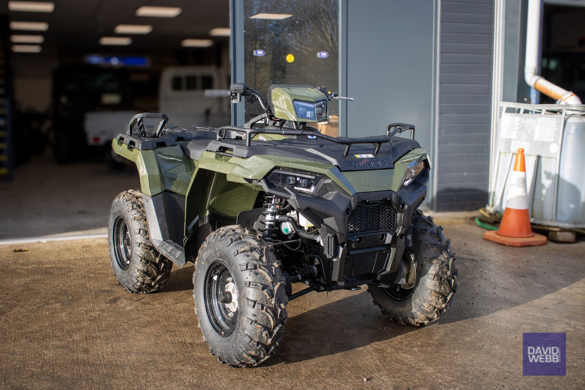 A green atv is parked in front of a building.