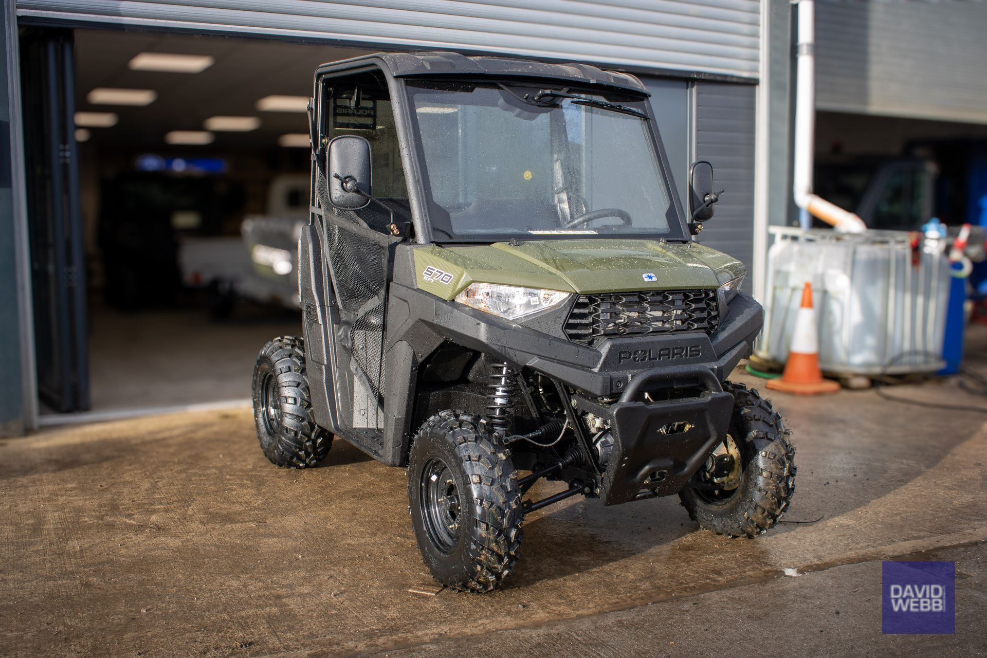 A green atv is parked in front of a garage.