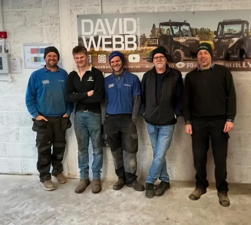A group of men standing in front of a sign that says david webb