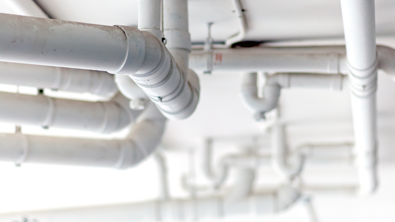 A bunch of white pipes hanging from the ceiling of a building.