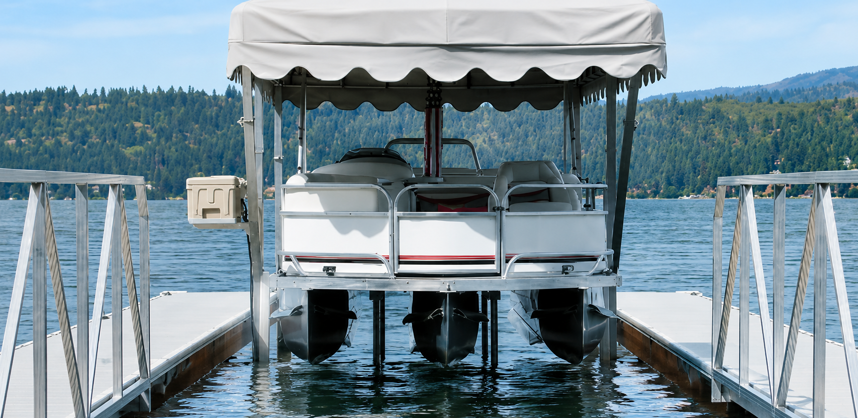 Pontoon boat at a dock on a lake, viewed from the stern under a white canopy.