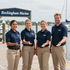 Four marina staff in navy polos and khaki pants standing on a dock at Rockingham Marina