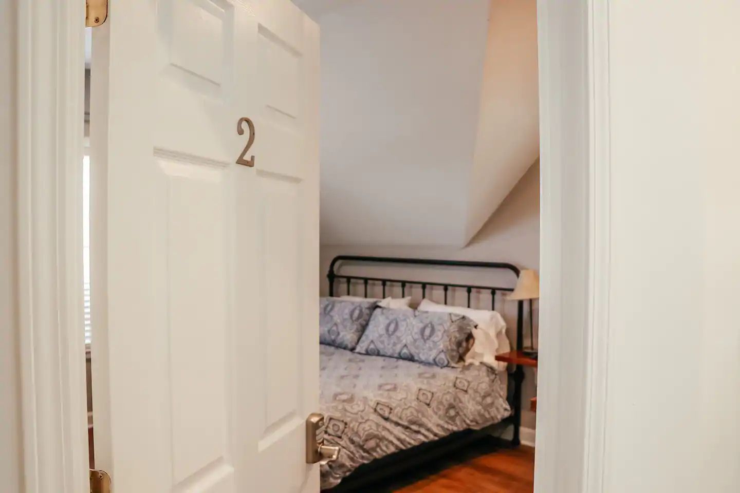 Open bedroom door labeled “2” revealing a bed with patterned bedding in a small room.
