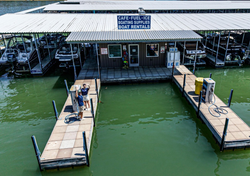 Learn More About Rockingham Marina Floating marina docks beside a green lakefront building with boats covered in slips
