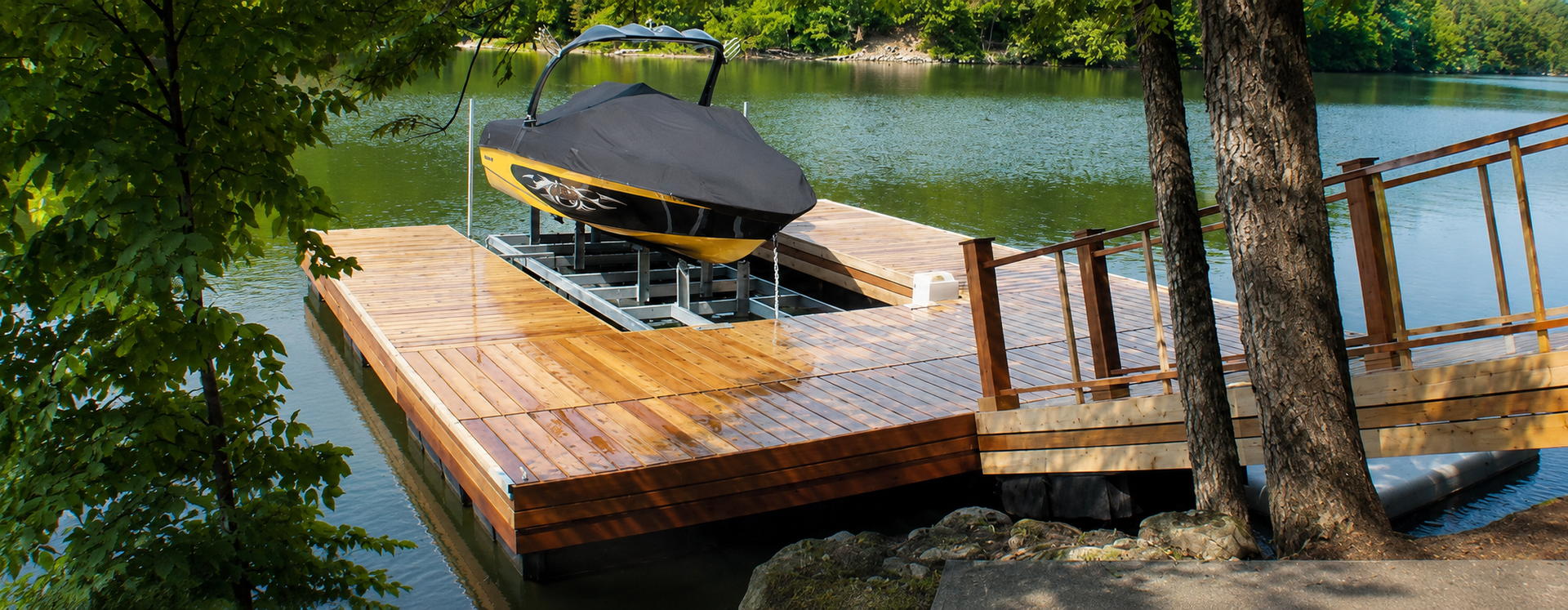Wooden lakeside dock with a covered bench and railings beside calm water and trees