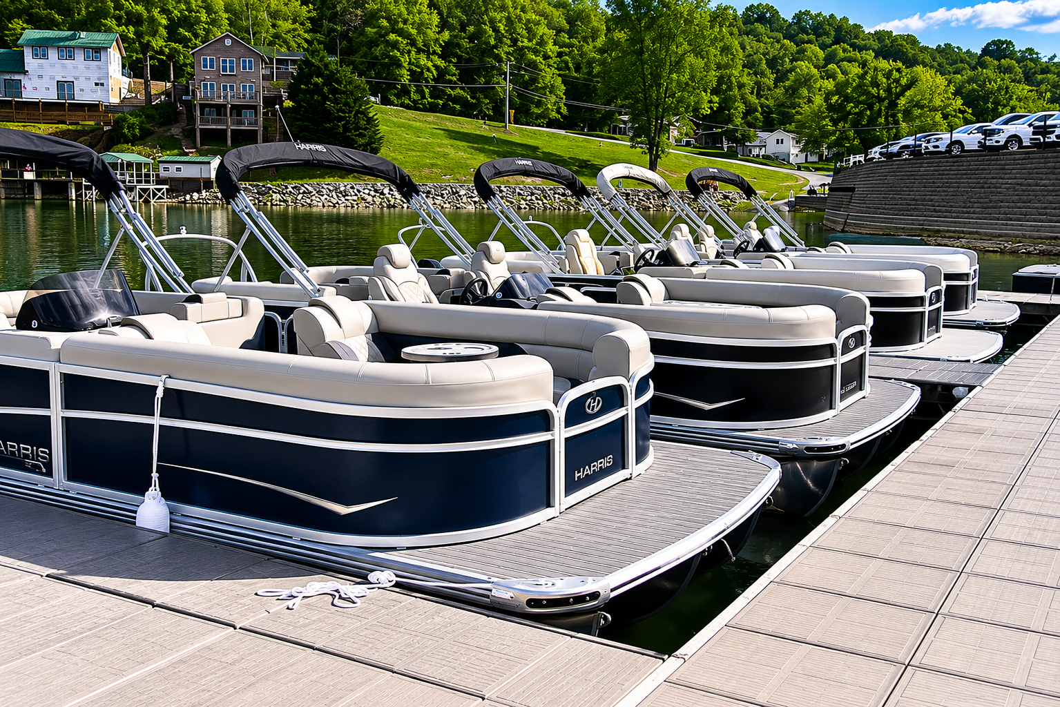 Row of black pontoon boats moored at a marina beside a paved dock and green shoreline