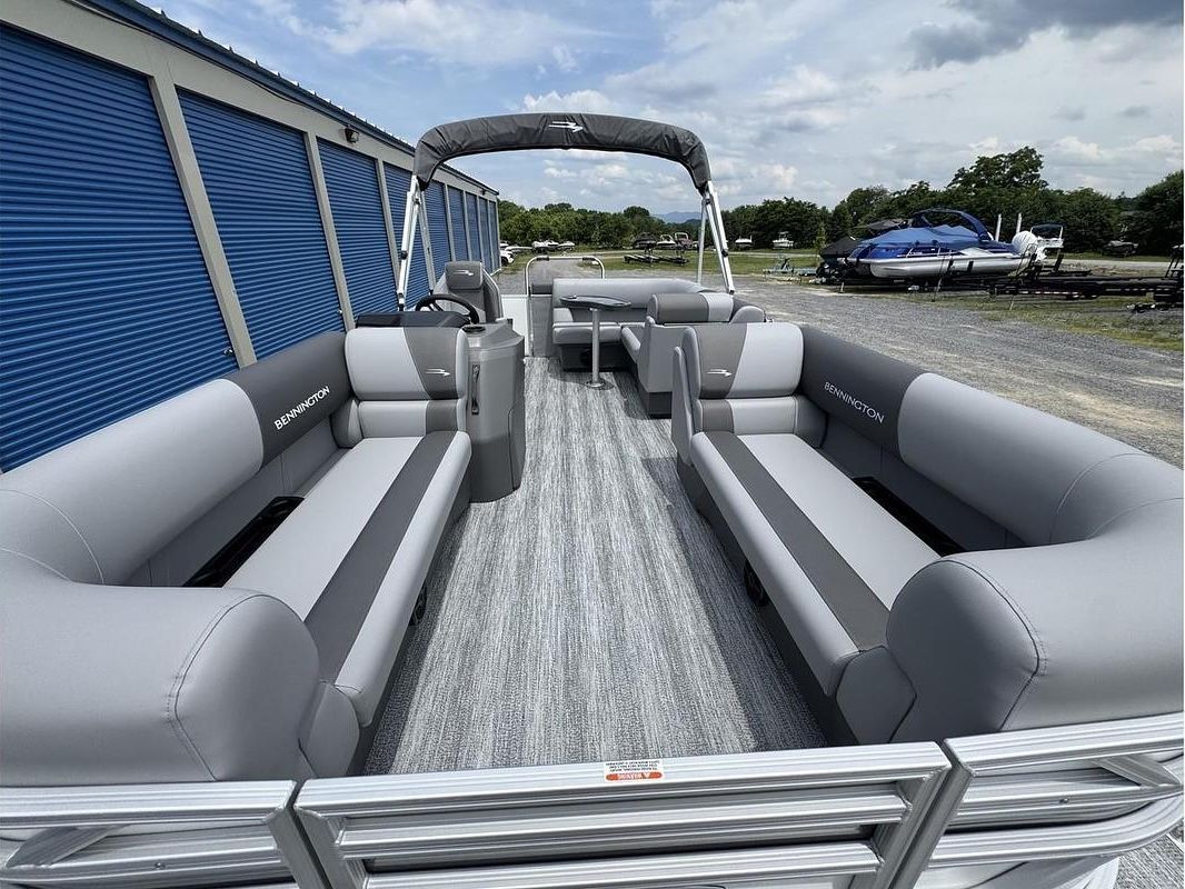 Rent This Boat! Gray upholstered seating in an outdoor open-air boat or pontoon, with a canopy and docked nearby