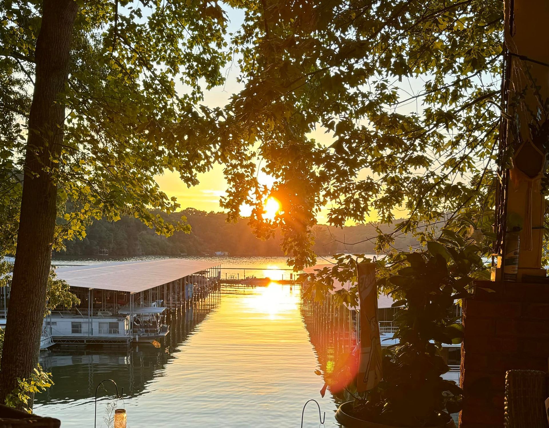 Sunset over a calm marina, with boats docked along a tree-framed waterway.