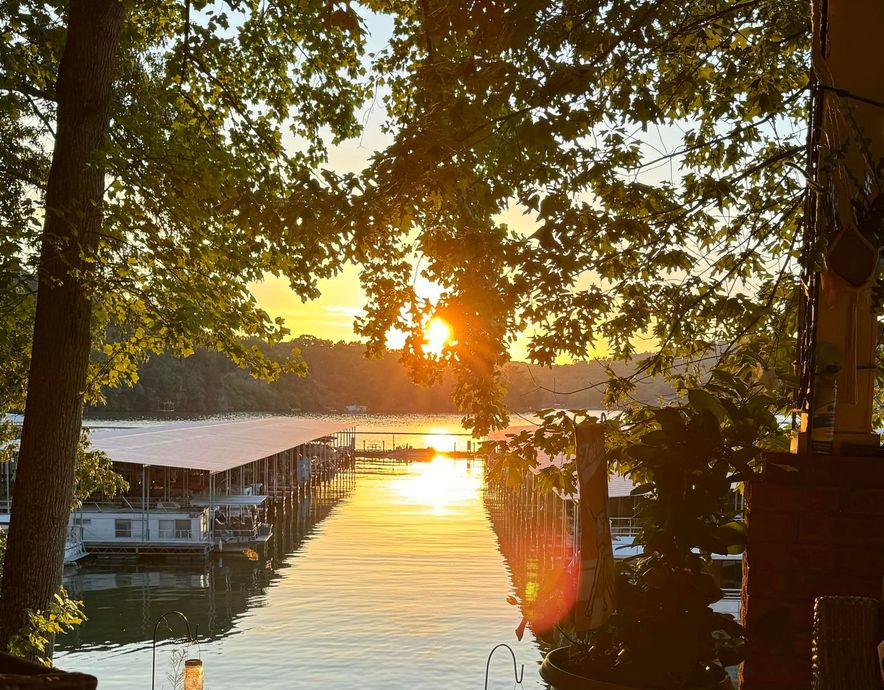 Sunset over a calm marina, with boats and docks framed by trees