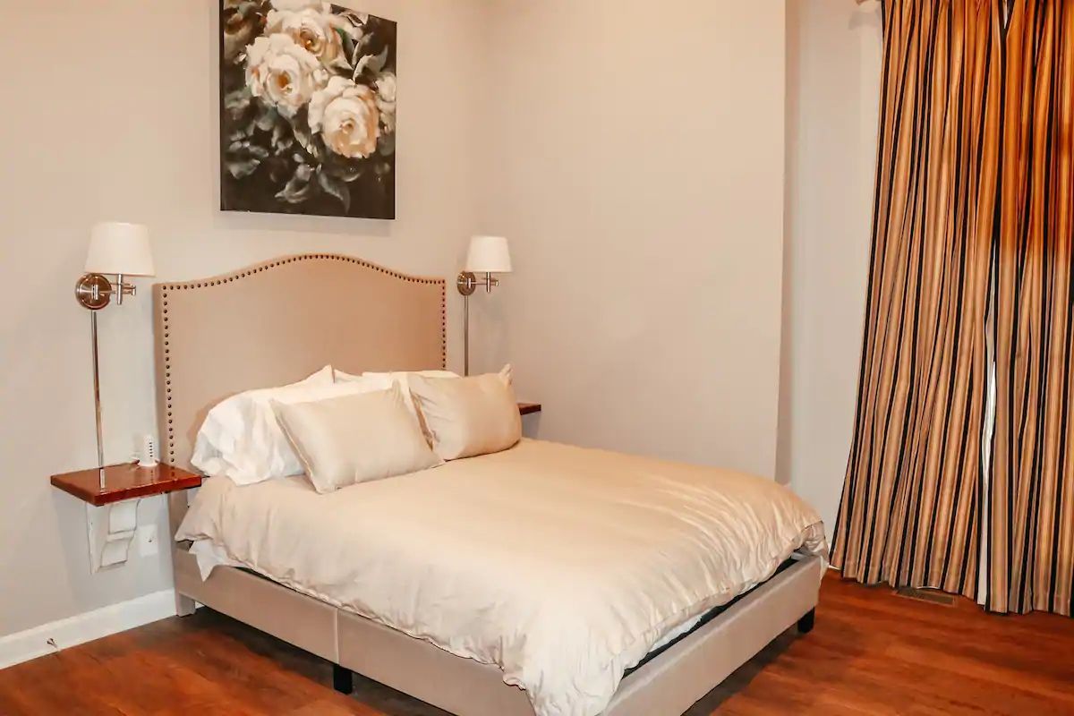 Cozy bedroom with a bed, floral wall art, bedside lamps, and striped curtains