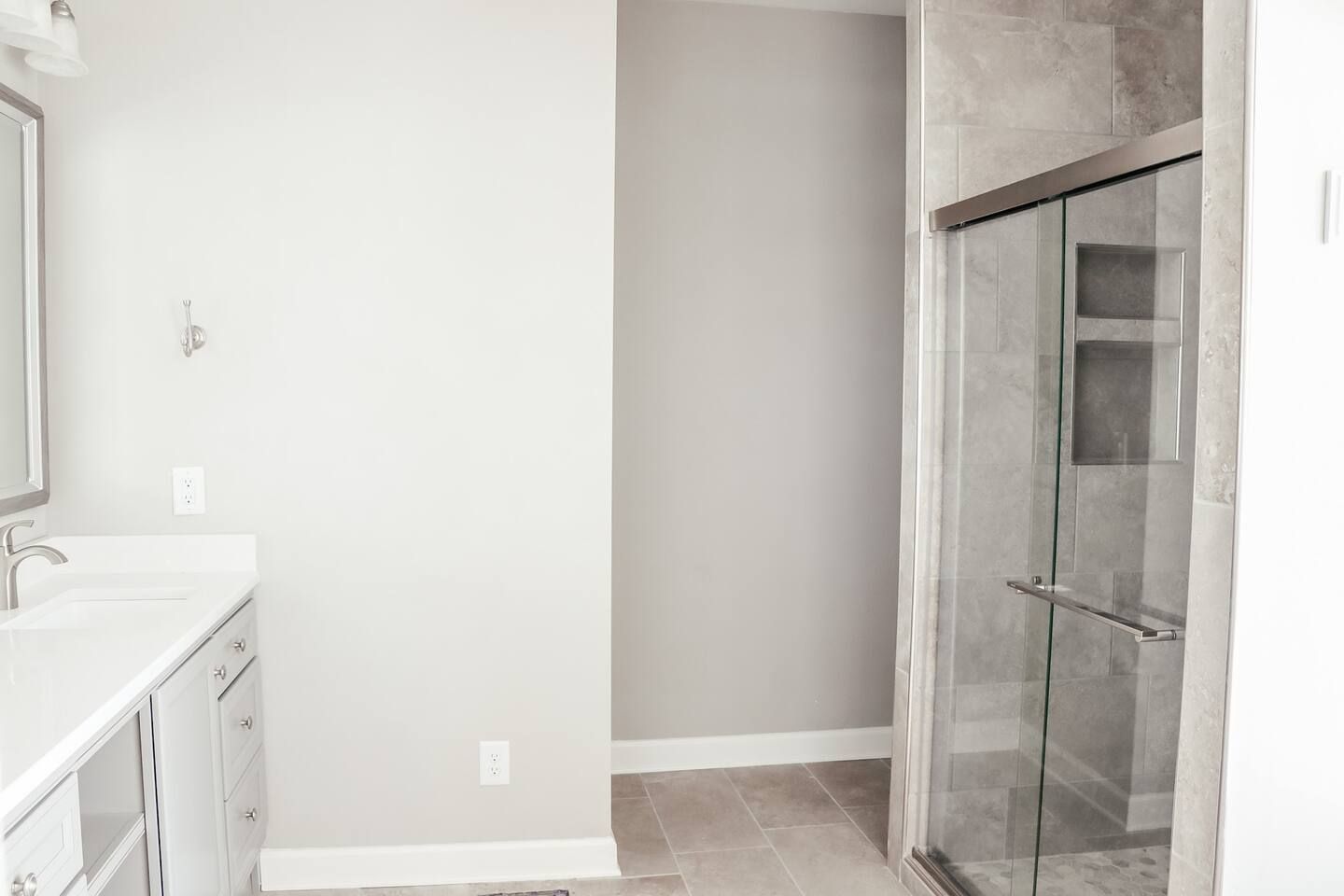 Small bathroom with white vanity, gray walls, and glass shower door.