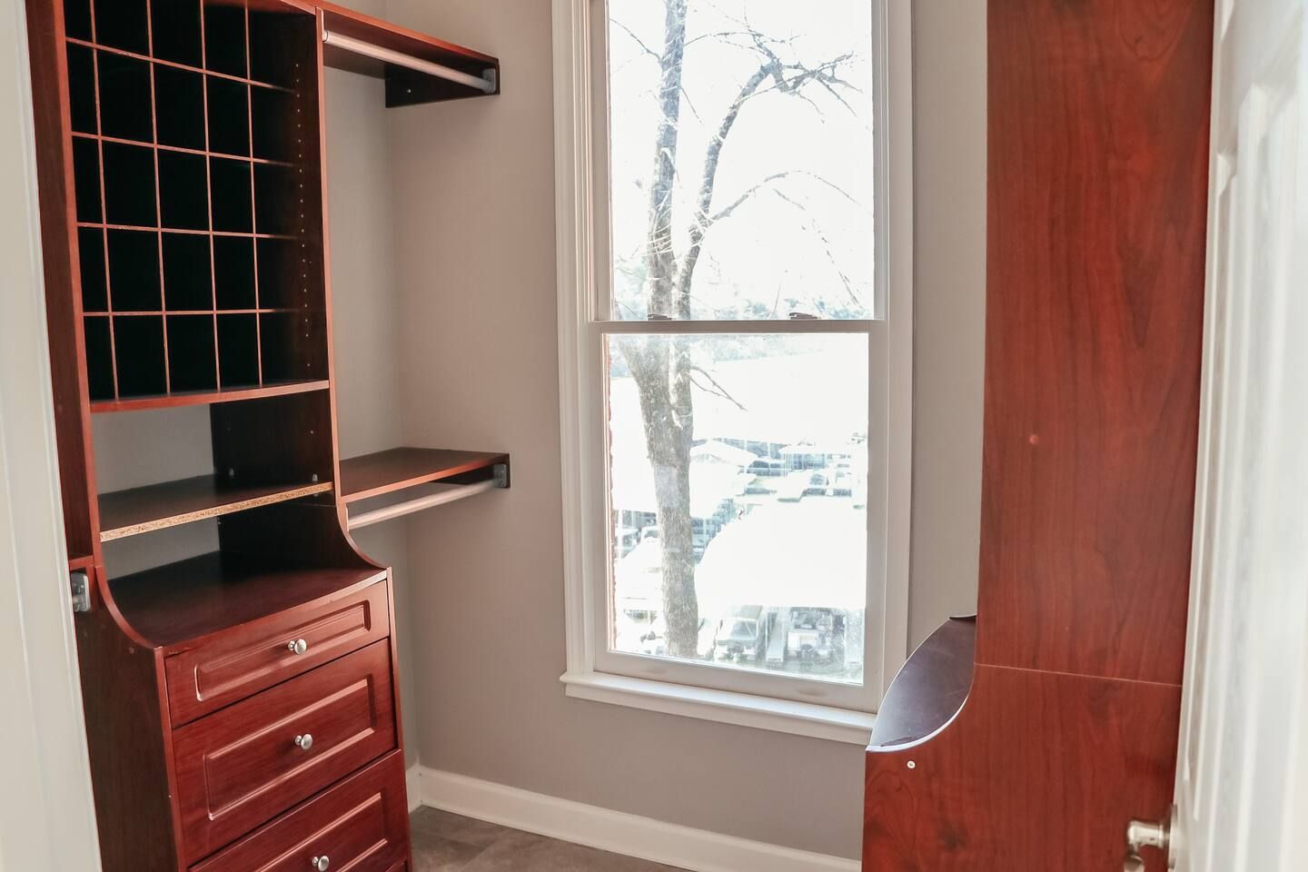 Small built-in wooden desk nook with drawers and shelves beside a window