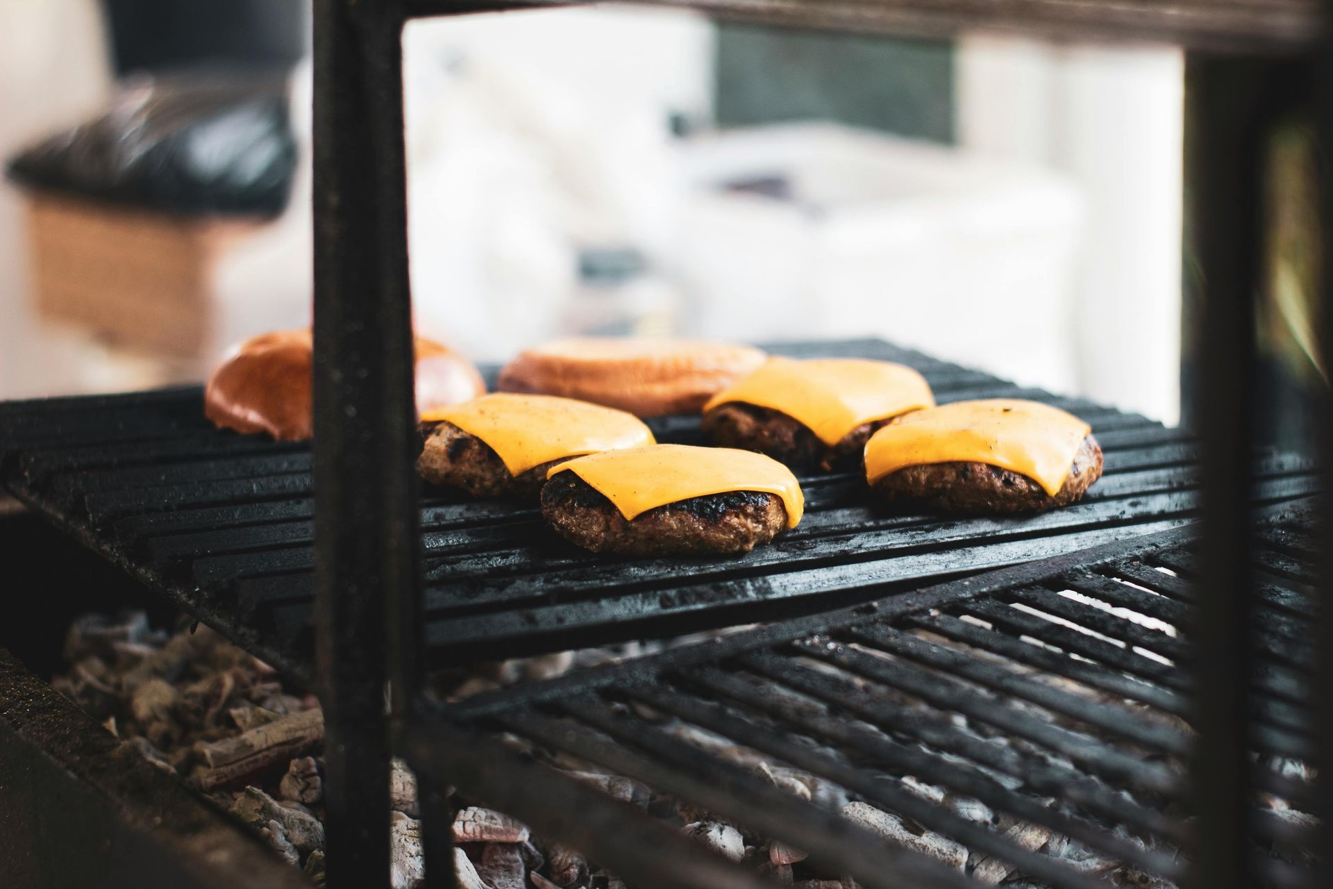 Burgers with melted cheese grilling on a barbecue rack