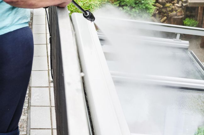 A man is using a high pressure washer to clean a railing