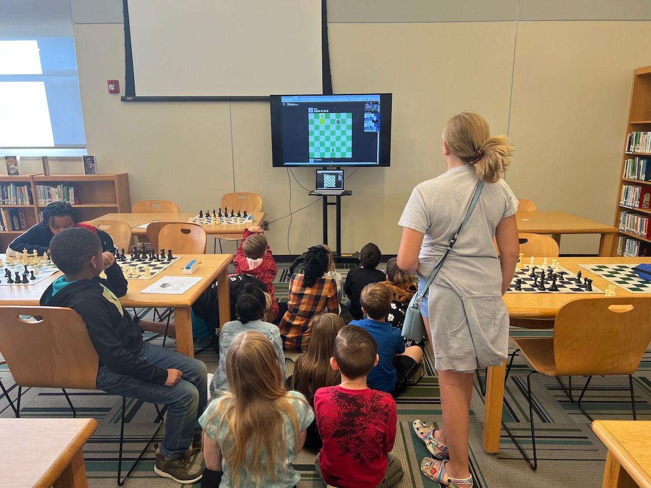 A group of children are playing chess in a library.