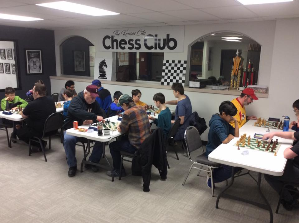 A group of people are playing chess in a chess club