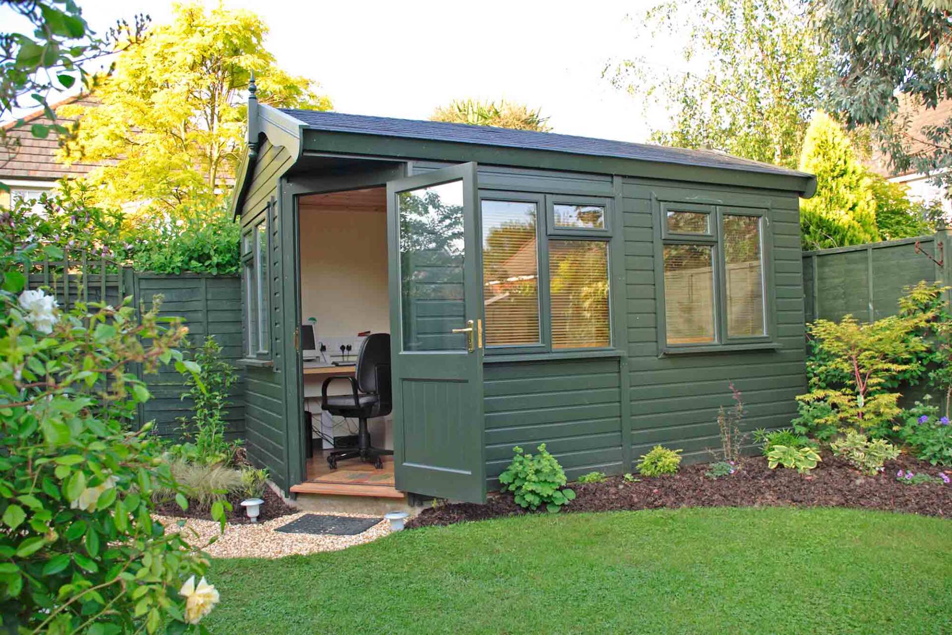 Green timber office installed in suburban garden